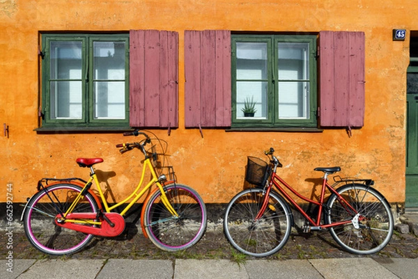 Obraz Bicycles in front of an orange house facace in Nyboder (historic row house district of former Naval barracks in Copenhagen, Denmark).