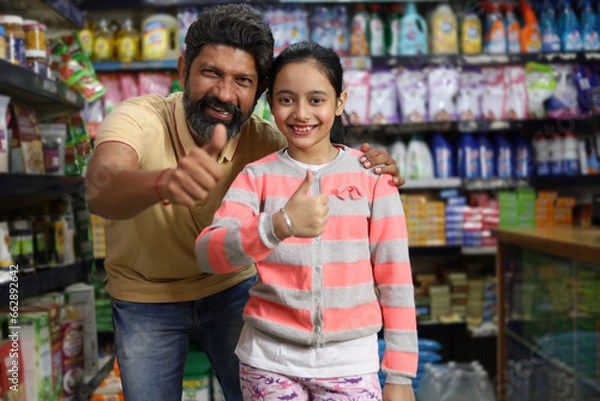 Obraz Happy Indian father with daughter enjoying purchasing in grocery store. Buying grocery for home in supermarket. Funny moments in retail store.