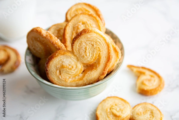Obraz Puff pastry palmiers in a bowl on a white marble table. Homemade bakery.