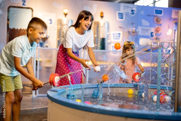 Obraz Mom with kids play with balls, learning physical phenomena in an interesting way, having fun in a science museum with interactive models