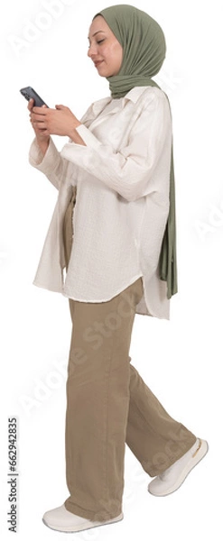 Fototapeta Walking using mobile phone, full length body view caucasian muslim woman in hijab walking using mobile phone. Holding smartphone technology device taking step. Messaging, browsing, social media.