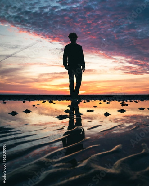 Obraz Silhouette of a man walking on a beach at dusk