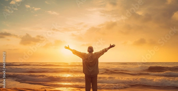 Obraz silhouette of an old man with stretched arms greeting the sun on a beach