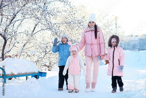 Fototapeta Family with children play snowy winter games in the park. Winter holidays and family vacation. Winter walk on the street on a sunny frosty day.