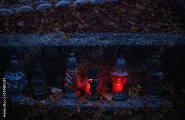 Obraz Votive candles lantern burning on the graves in Slovak cemetery at night time. All Saints' Day. Solemnity of All Saints. Hallows eve. 1st November. Feast of Saints. Hallowmas. Souls' Day in Slovakia