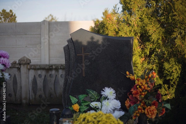 Obraz Blank headstone in the Christian cemetery. Close up of a single empty tombstone at European graveyard. Place for text on gravestone. Tombstone with flower decoration and trees. Autumn scene