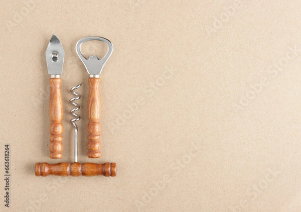 Fototapeta bar set (bottle opener, wine opener, can opener) on brown paper background with copy space