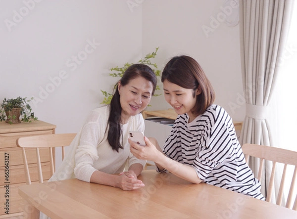 Obraz 携帯を見ながら笑顔で話しをする仲良し母娘