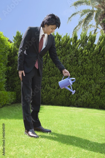 Fototapeta ジョウロで水やりをするビジネスマン