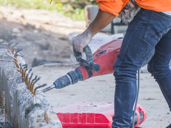 Fototapeta Workers use a jackhammer to break concrete.