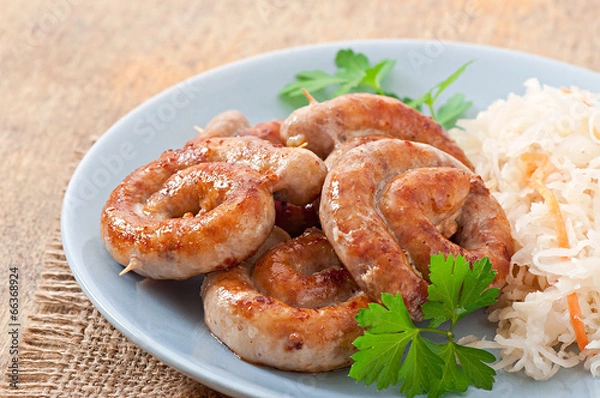 Fototapeta Bavarian fried sausages on sauerkraut