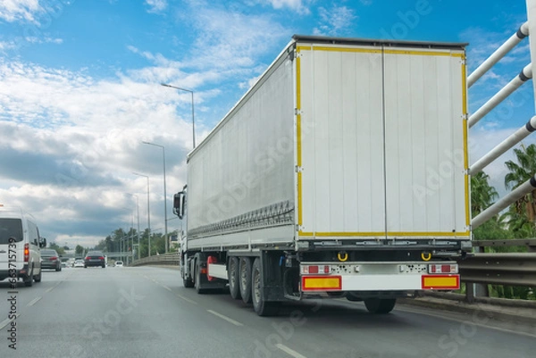 Fototapeta Truck transportation on the road on a highway bridge in the city on a nice clear summer day.