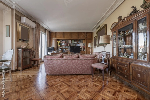 Fototapeta Apartment furnished in vintage style with lots of wood, hardwood parquet floors and sofas with patterned upholstery