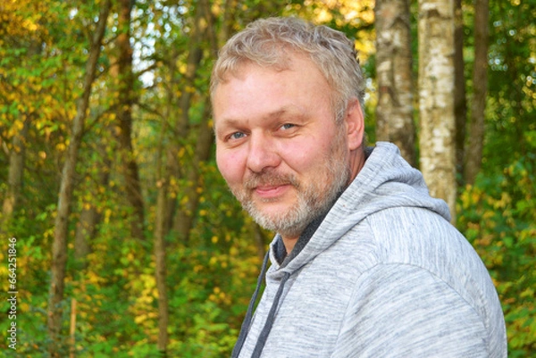 Fototapeta Gray-haired man with beard on honking in autumn park