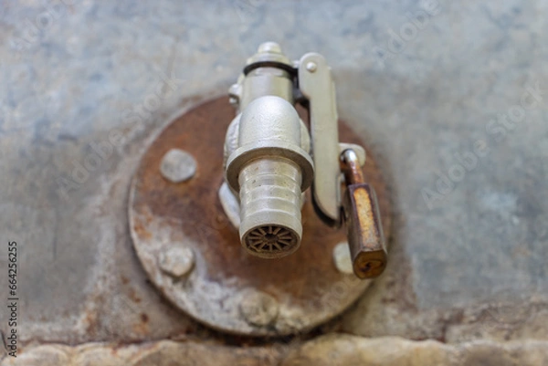 Obraz A water tap on the cistern locked with a padlock, close up