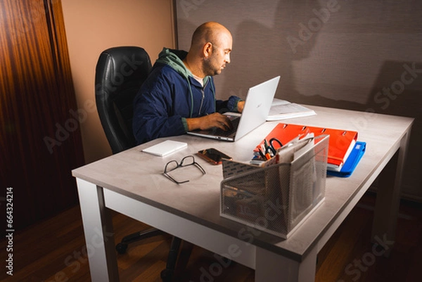 Obraz Boy working at home. With a computer, cell phone, clothes, files