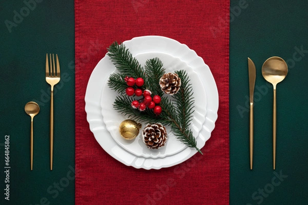 Obraz Festive table setting, christmas decoration. Dishware, golden cutlery. Celebration xmas eve: exquisite arrangement, red accent. Gold bauble, fir cones, evergreen tree. Holiday banquet, view from above