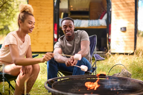 Obraz Close Up Of Couple Camping In Countryside With RV Toasting Marshmallows Outdoors On Fire