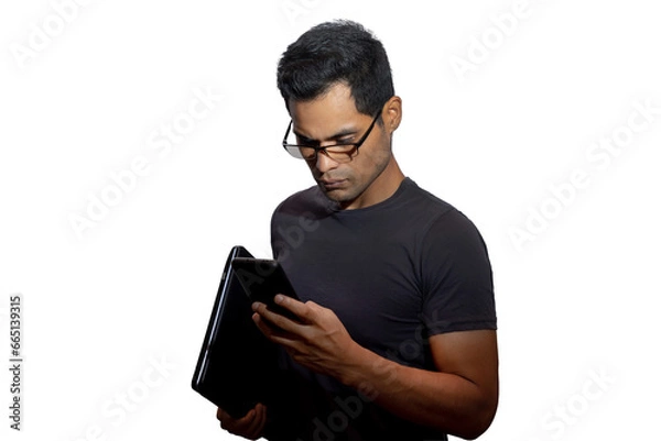 Fototapeta Young Latino with glasses and laptop, looking serious at his phone. Networking concept, programming, business, cybersecurity. Isolated.