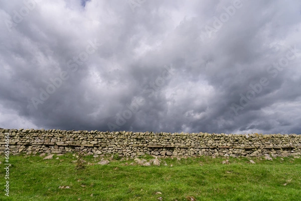 Obraz an old stone wall with stormy skies behind, from Hadrian's Wall Path near Once Brewed, Northumberland, UK