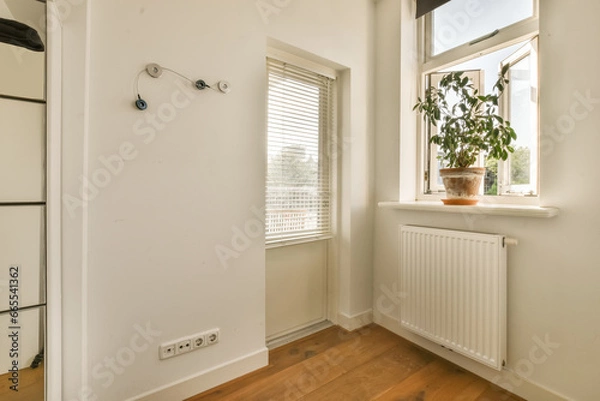 Fototapeta a white room with wood flooring and a window that has shutters on the outside wall to let in natural light