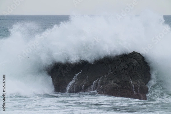 Fototapeta 岩にあたり飛び散る波しぶき
