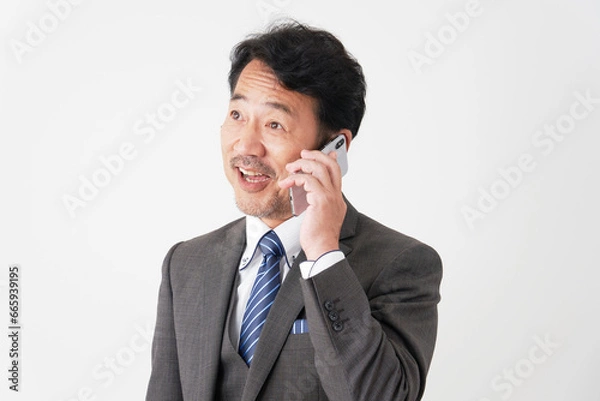 Fototapeta スマートフォンで電話する中年のビジネスマン　白背景