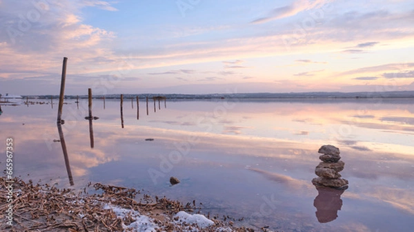 Fototapeta Sunset on the salt lagoon with reflections of clouds and silhouettes of reflections