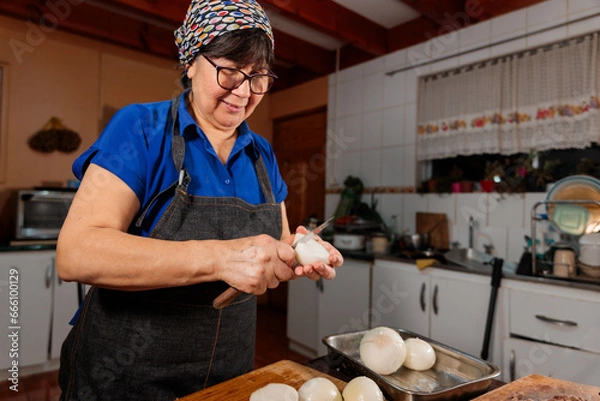 Fototapeta Low angle view of unrecognizable latin woman chopping onion with a knife, for filling homemade baked empanadas