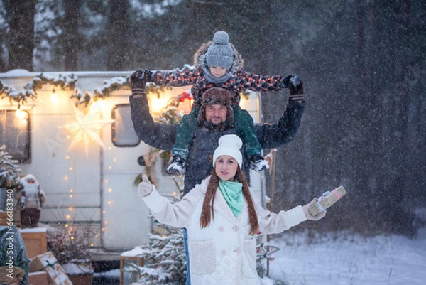 Fototapeta Family concept. Portrait of happy family father and mother with son in winter nature in snowy forest. Enjoying spending time together.