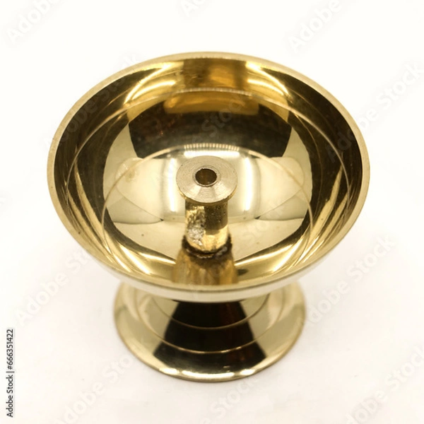Fototapeta a symmetric golden oil diya lamp with a wick stand made of brass used for temple worship isolated in a white background