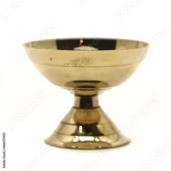 Fototapeta a symmetric golden oil diya lamp with a wick stand made of brass used for temple worship isolated in a white background