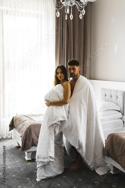 Fototapeta Couple in love posing in blankets in a hotel room in the mountains. Concept for a vacation in the mountains