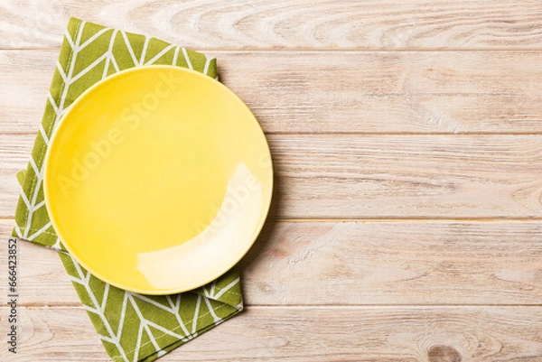 Obraz Top view on colored background empty round yellow plate on tablecloth for food. Empty dish on napkin with space for your design
