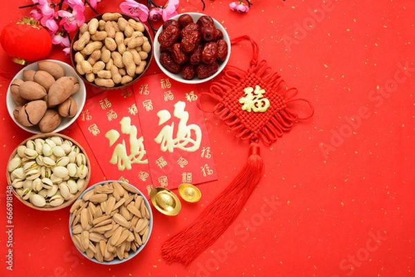 Obraz On the red background of the Chinese New Year, there are nut snacks, red envelopes, ingots, preserved plums, and lanterns. The Chinese meaning in the picture is: good luck