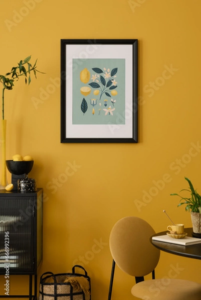 Fototapeta Stylish composition of warm dinning room interior with mock up poster frame, round table, yellow chair, glass vase with dried flowers, lamp, and personal accessories. Home decor. Template.