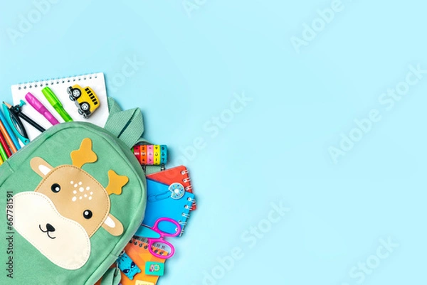 Fototapeta Back to school, education concept Deer green backpack with school supplies - notebook, pens, eraser rainbow, numbers isolated on blue background Top view Copy space Flat lay composition