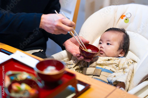 Fototapeta 生後100日のお食い初めでパパにもらうご飯を不思議そうに見つめる生後3か月の赤ちゃん