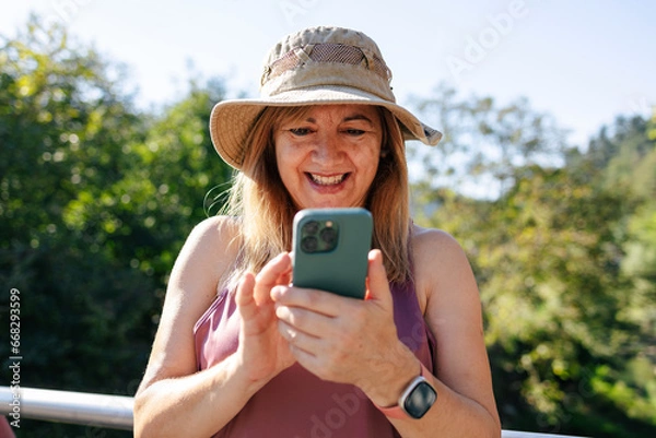 Obraz Adult woman smiling looking at smart phone