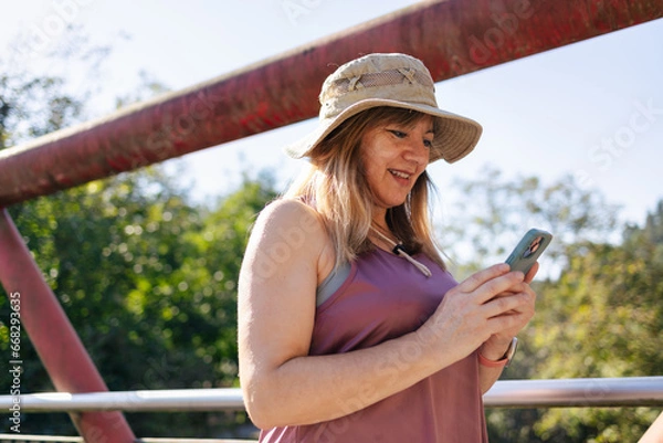 Obraz Adult woman smiling looking at smart phone