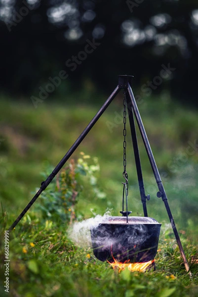 Fototapeta Cauldron with food and steam over fire