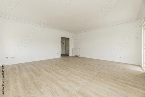 Fototapeta Large empty room with plain white painted walls and light wooden floors