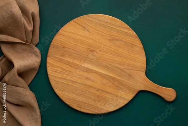 Obraz Round empty wooden charcuterie serving board with handle on old green concrete background, table top view. Food template with copy space. Flat lay design, mock up. Layout, cooking concept, frame