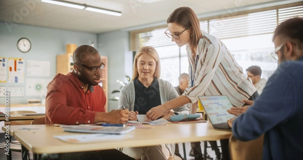 Fototapeta Grown-Up Men and Women Working in Groups for an Assignment in Specialty Development Center. Adult Classmates Working on a Team Assignment, Young Female Teacher Explaining the Exercise Goals.