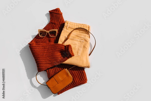 Fototapeta Knitted brown sweater with pants and handbag. Women's warm jumper, stylish autumn or winter clothes. Fashion autumnal outfit. Cozy bright  fall look. Flat lay, top view.