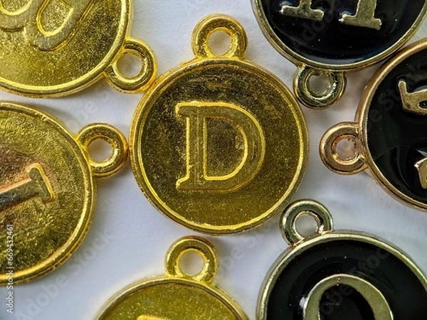 Fototapeta gold initial 'D' pendant in the middle of several letters