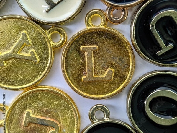 Fototapeta gold initial 'L' pendant in the middle of several letters