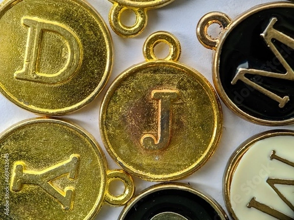 Fototapeta gold initial 'J' pendant in the middle of several letters