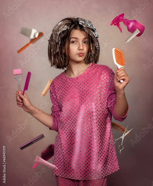 Obraz A girl in home clothes dyes her hair. The girl holds brushes and combs in her hands. A girl does her hair at home.