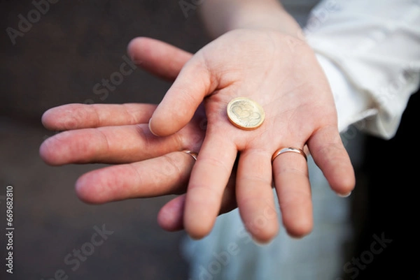 Fototapeta Bride and Groom's Hands Together Holding a Coin with Heart Symbol Close-Up